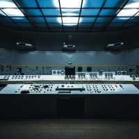 九七电影院 技术人员在夜间值守屏幕前监测多条播放线路延迟曲线，屏幕蓝光映在面部